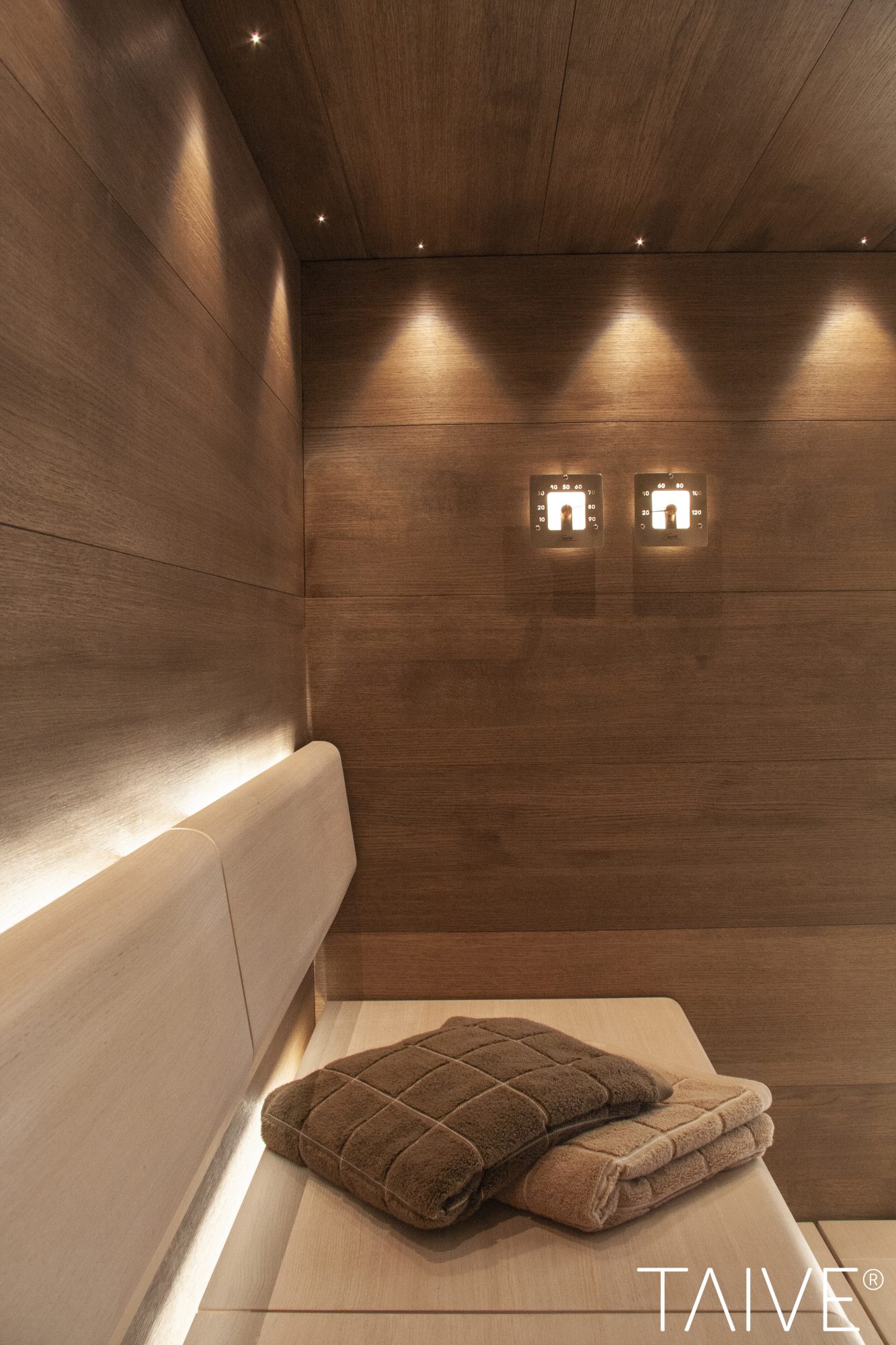 Cariitin Taive sauna linear valaistuksella lauteilla, kuidut katossa, valaistut mittarit.